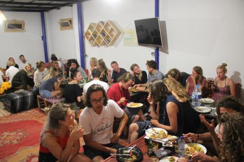 塔姆拉赫特乌兹达尔Sunset Surfhouse Morocco的一群坐在餐桌上吃食物的人