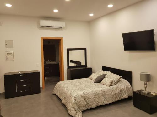 普拉亚达维多利亚Black House的卧室配有一张床,墙上配有电视。