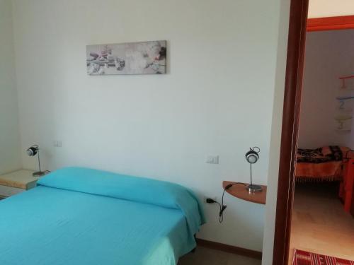 普佐伊杜撒丁岛海洋公寓的一间卧室配有一张蓝色的床和一张桌子