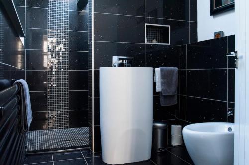 韦尔斯Boutique house central Wells的黑色瓷砖浴室设有水槽和卫生间