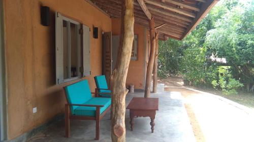 KalametiyaTaragala Chalets的房屋门廊上的两把椅子和一张桌子