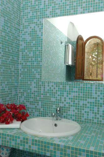 兰佩杜萨艾旦慕斯迪博尔戈卡拉克雷塔酒店的绿色瓷砖浴室设有水槽和镜子