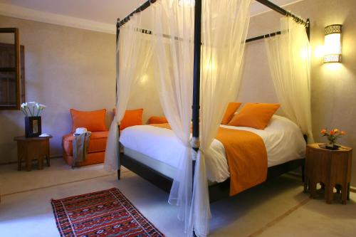 马拉喀什Riad CHERRATA的一间卧室配有两张床和一张天蓬床。