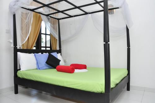 米瑞莎米瑞莎博爱考迪住宿加早餐旅馆的一间卧室配有黑色和绿色的天蓬床和色彩缤纷的枕头。