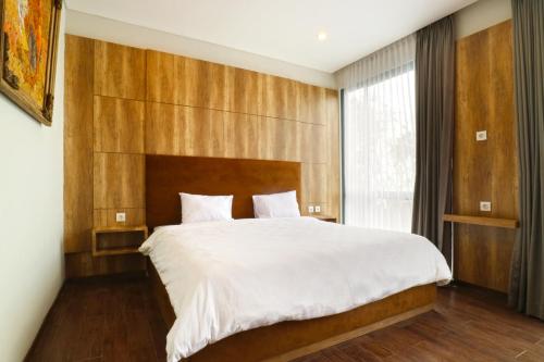 金巴兰金巴兰普拉纳别墅酒店的一间卧室配有一张大床和木制床头板