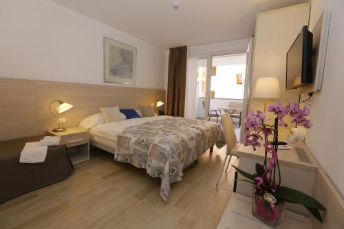 格拉多Hotel & Apartments Eldorado的配有床和鲜花桌的酒店客房