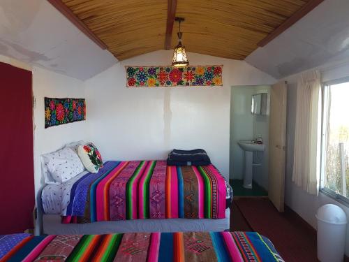 普诺Uros Lake Titicaca Lodge的一间卧室配有一张带彩色毯子的床
