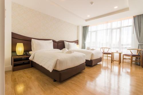 达叻府阿瓦达酒店的酒店客房设有两张床和一张桌子。
