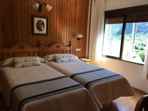 托尔拉Hotel Bellavista Ordesa的配有窗户的酒店客房内的两张床