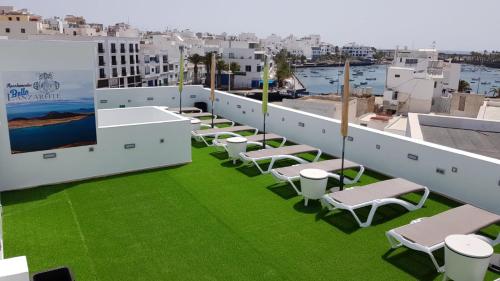 阿雷西费Apartamentos Bello Lanzarote的绿草丛生的屋顶上一排椅子