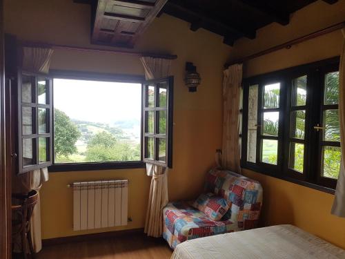 里瓦德塞利亚Hotel Rural La Curva Ribadesella的一间卧室配有一张床、一把椅子和窗户。