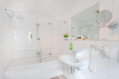 蒂门多弗施特兰德Strandgrün Golf- & Spa Resort的白色的浴室设有水槽和淋浴。