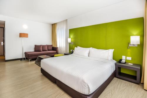 卡塔赫纳博卡格兰德智选假日酒店的酒店客房设有一张大床和绿色的墙壁。