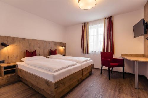 ObertaufkirchenBrauerei Gaststätte Stierberg的一间卧室配有一张大床和一张红色椅子