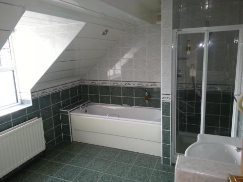 惠特利湾温莎酒店的设有带浴缸和淋浴的浴室。