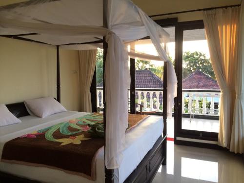 罗威那曼德哈拉奇科洋房酒店的一间卧室设有一张天蓬床和一个阳台