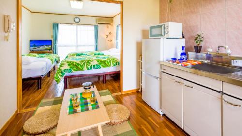读谷村日落赞帕酒店的带冰箱的厨房和客房内的一张床