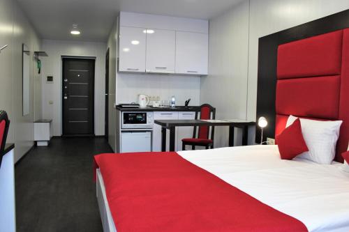巴尔瑙尔福克斯城市酒店的一间带红色床的卧室和一间厨房