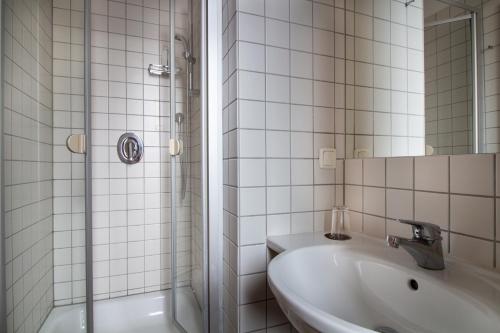 曼海姆Hotel Goldene Gans的白色瓷砖浴室设有水槽和淋浴