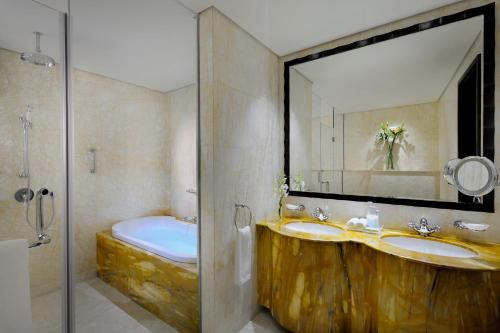 迪拜Crowne Plaza - Dubai Jumeirah, an IHG Hotel的浴室设有2个水槽、镜子和浴缸。