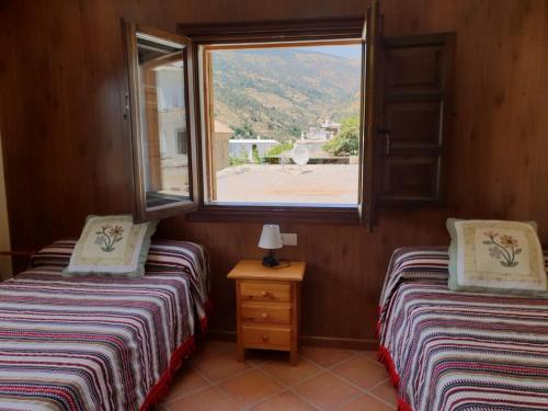 潘潘埃拉Hostal Pampaneira的带窗户的客房内设有两张单人床。