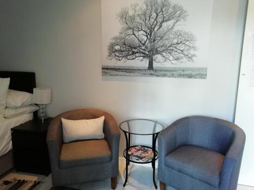 开普敦The Palm的卧室配有两把椅子,墙上挂着一幅树画