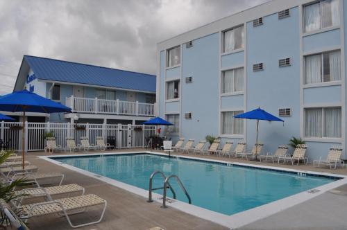大洋城海岸旅馆 - 大洋城的酒店前的游泳池配有椅子和遮阳伞