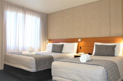 汉密尔顿汉密尔顿文图拉套房酒店的酒店的客房 - 带2张带白色枕头的床