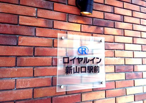 山口Royal Inn Shinyamaguchi Ekimae的砖墙边的标志