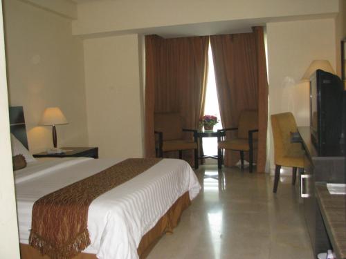 雅加达Grand Asia Hotel Jakarta的酒店客房设有一张大床和一台电视。