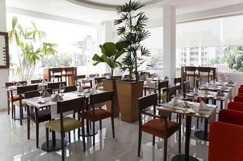 金沙萨Hotel Bella Riva Kinshasa的餐厅设有桌椅和大窗户。
