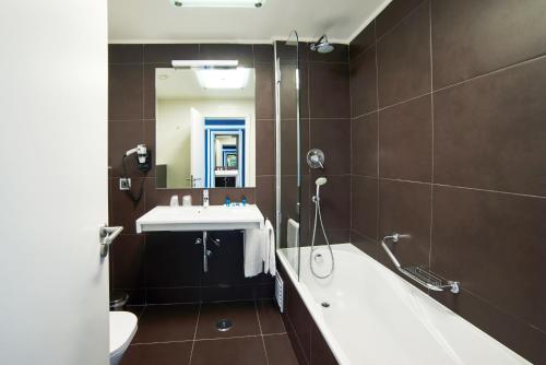 阿尔沃尔RR Alvor Baía Resort的带浴缸、水槽和镜子的浴室