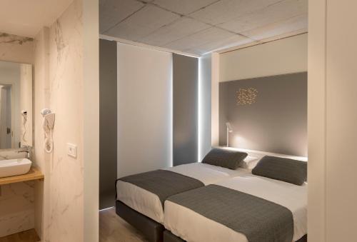 菲尼斯特雷Hotel SempreFisterra的一间卧室设有两张床和盥洗盆