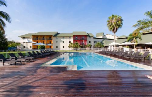 卡宴Grand Hotel Montabo的一座带椅子的度假村的游泳池和一座建筑