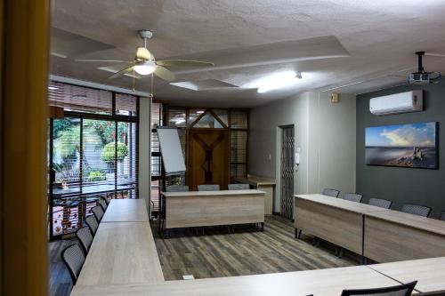 波罗瓜尼Polo Guest House的一间设有桌椅和吊扇的等候室