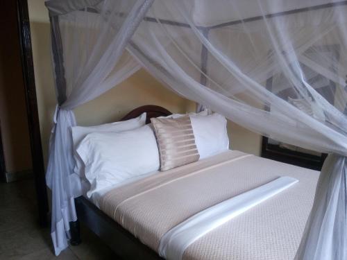 达累斯萨拉姆乌康佳中转汽车旅馆的卧室配有带白色床单和枕头的天蓬床。