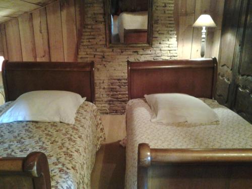 LaglorieuseLes Hotes Des Guillemets的一间卧室配有两张床和镜子