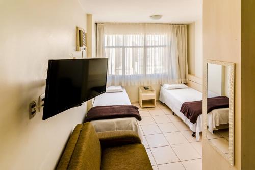 贝洛奥里藏特Villa Neves Residence的酒店客房设有两张床和一台平面电视。