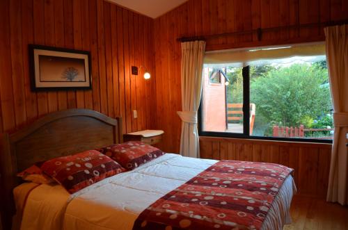弗鲁蒂亚尔Cabañas Entre Verdes的一间卧室设有一张床和一个大窗户
