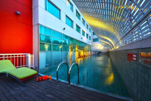 万隆哈里斯连城万隆节会议酒店的游泳池,位于旁边设有长凳的大楼