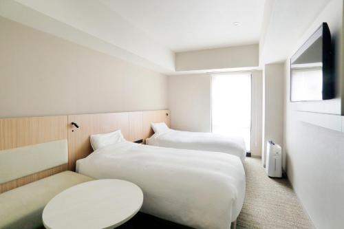 札幌札幌站南口JR酒店的酒店客房设有两张床和一张桌子。