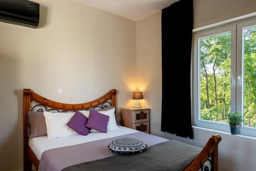 罗德岛卡利地亚Nicole's garden villa的一间卧室配有一张带紫色枕头的床和窗户。