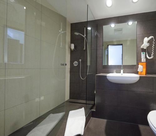 赫尔-格伦茨豪森斯里斯恩酒店的浴室配有盥洗盆和带镜子的淋浴