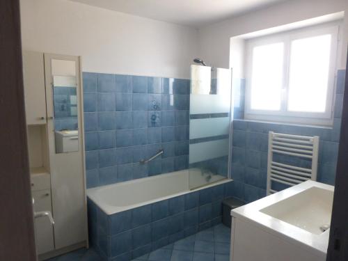 La Chapelle-AubareilLa Galinie的蓝色瓷砖浴室设有浴缸和水槽