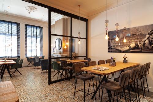 登博斯朱利安酒店的餐厅设有桌椅,墙上挂有绘画作品