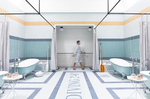 卡利斯托加Calistoga Motor Lodge and Spa, a JdV by Hyatt Hotel的一位妇女走进带两个浴缸的浴室