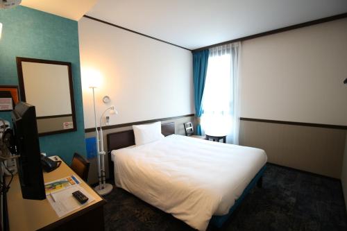 马赛东横马赛圣查尔斯酒店的一间酒店客房,配有一张白色的床和一张书桌