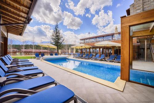 班斯科Katarino SPA Hotel的一座带蓝色躺椅的游泳池,位于大楼旁