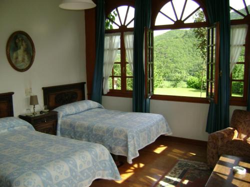CasoHotel Rural La Lastra的一间卧室设有两张床和大窗户