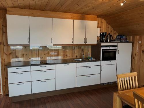 Gjesvær诺德卡普菲瑞公寓的厨房配有白色橱柜和木制天花板